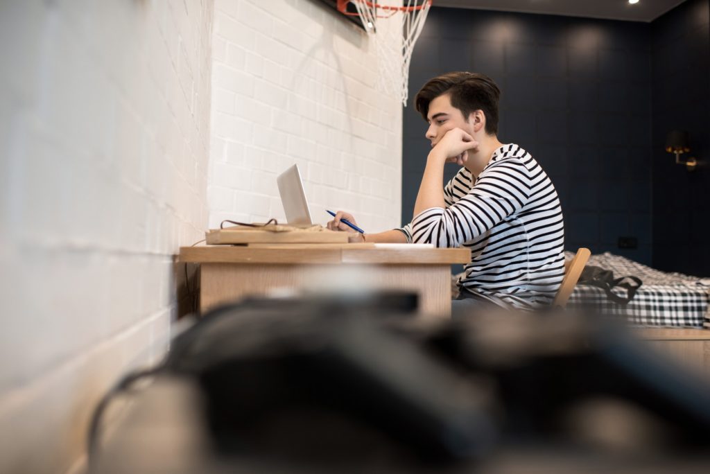 Concentrated young man sitting at home using laptop