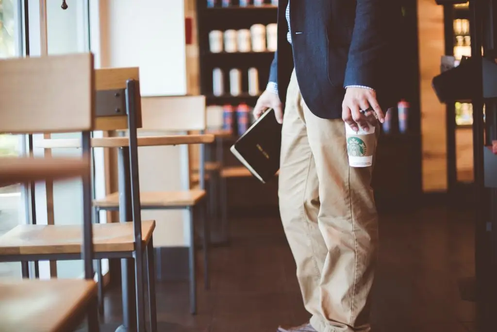 man holding Bible and coffee