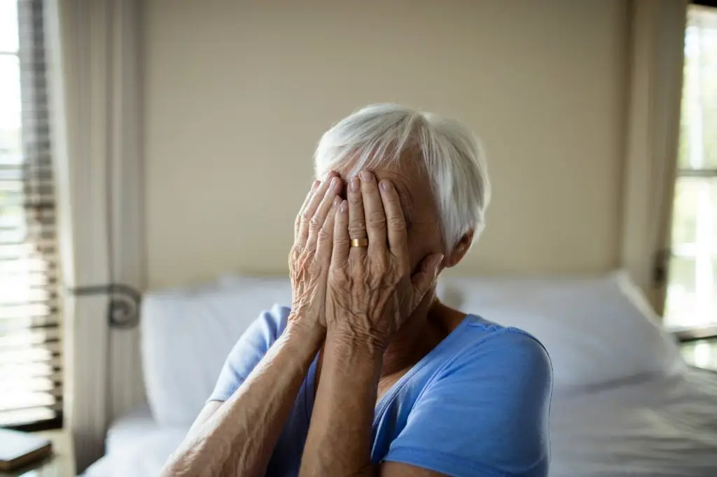 Stressed senior woman covering her face with hands